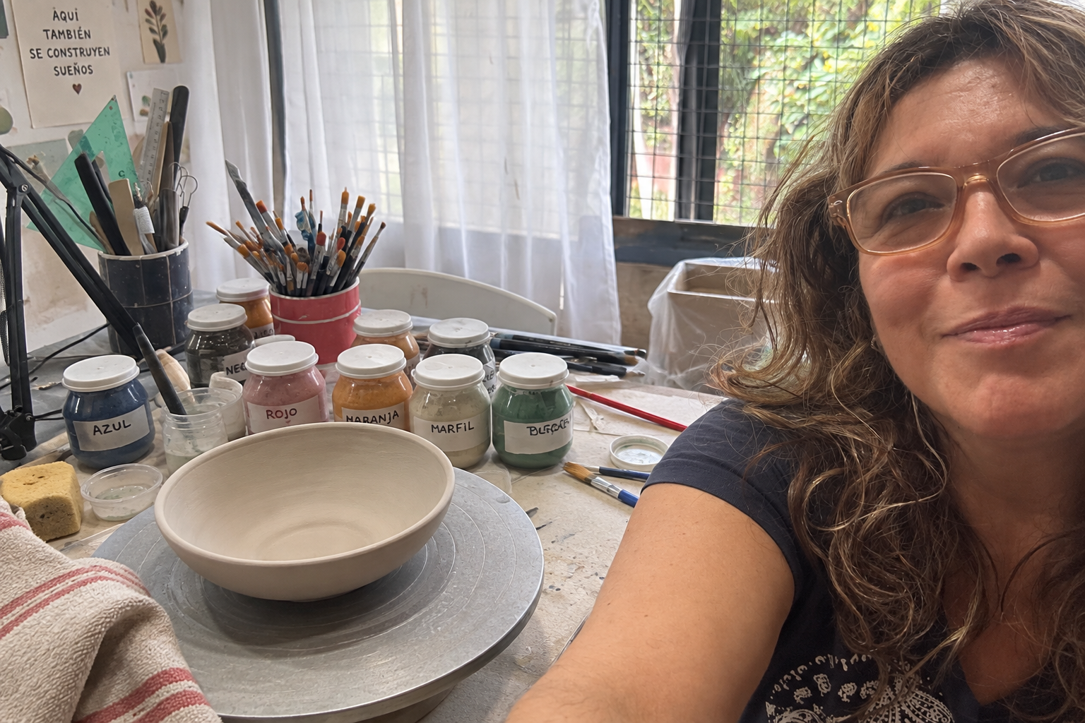 Ceci en su mesa de trabajo junto a una pieza cerámica y materiales del taller